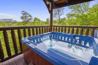hot tub on the deck of a cabin with a mountain view